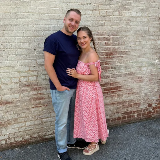 Tim and Elise Morgan standing together against a whitewashed brick wall