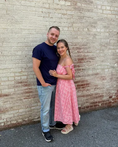 Tim and Elise Morgan standing together against a whitewashed brick wall